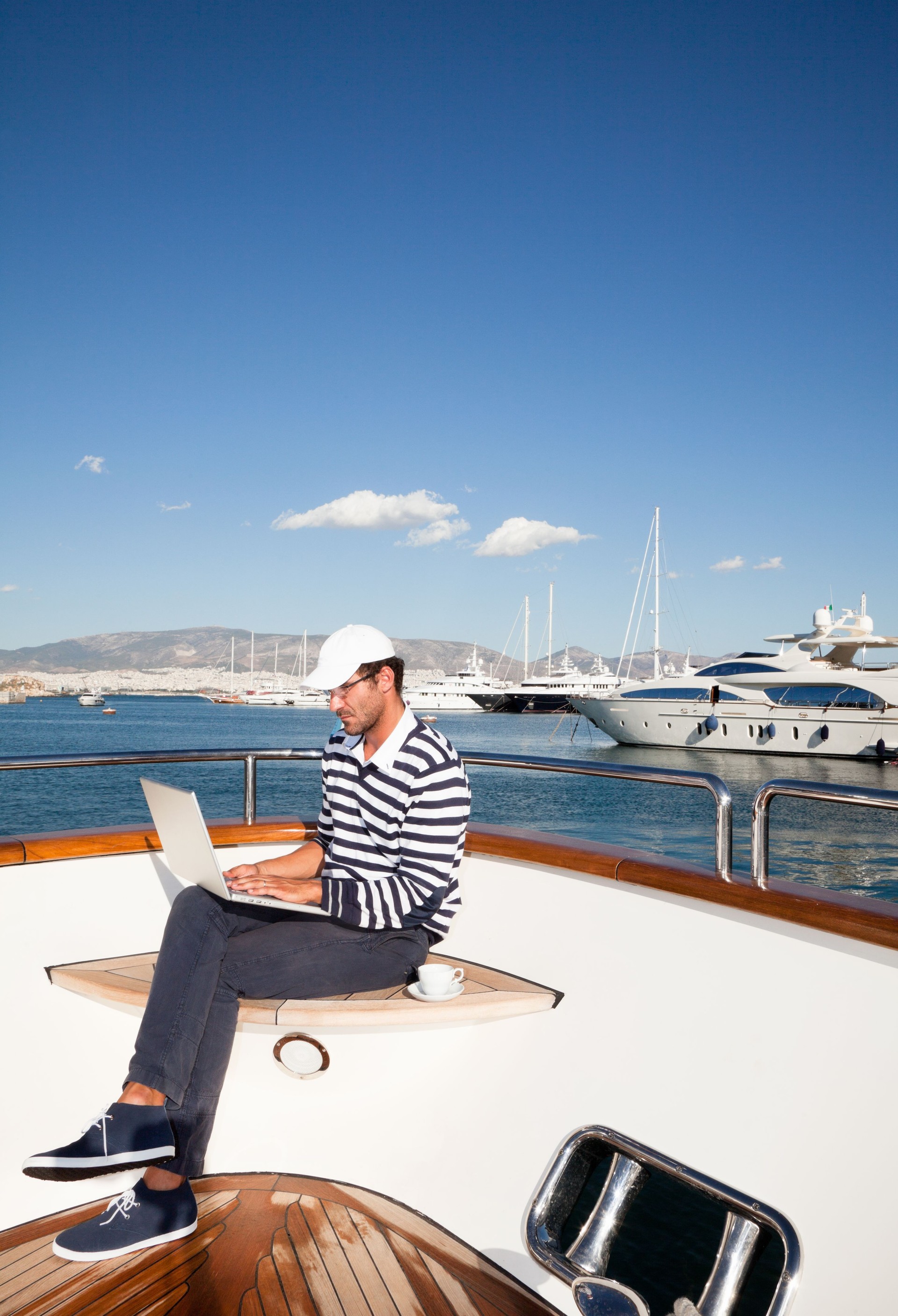Homme d'affaires à bord du yacht de travail avec ordinateur portable